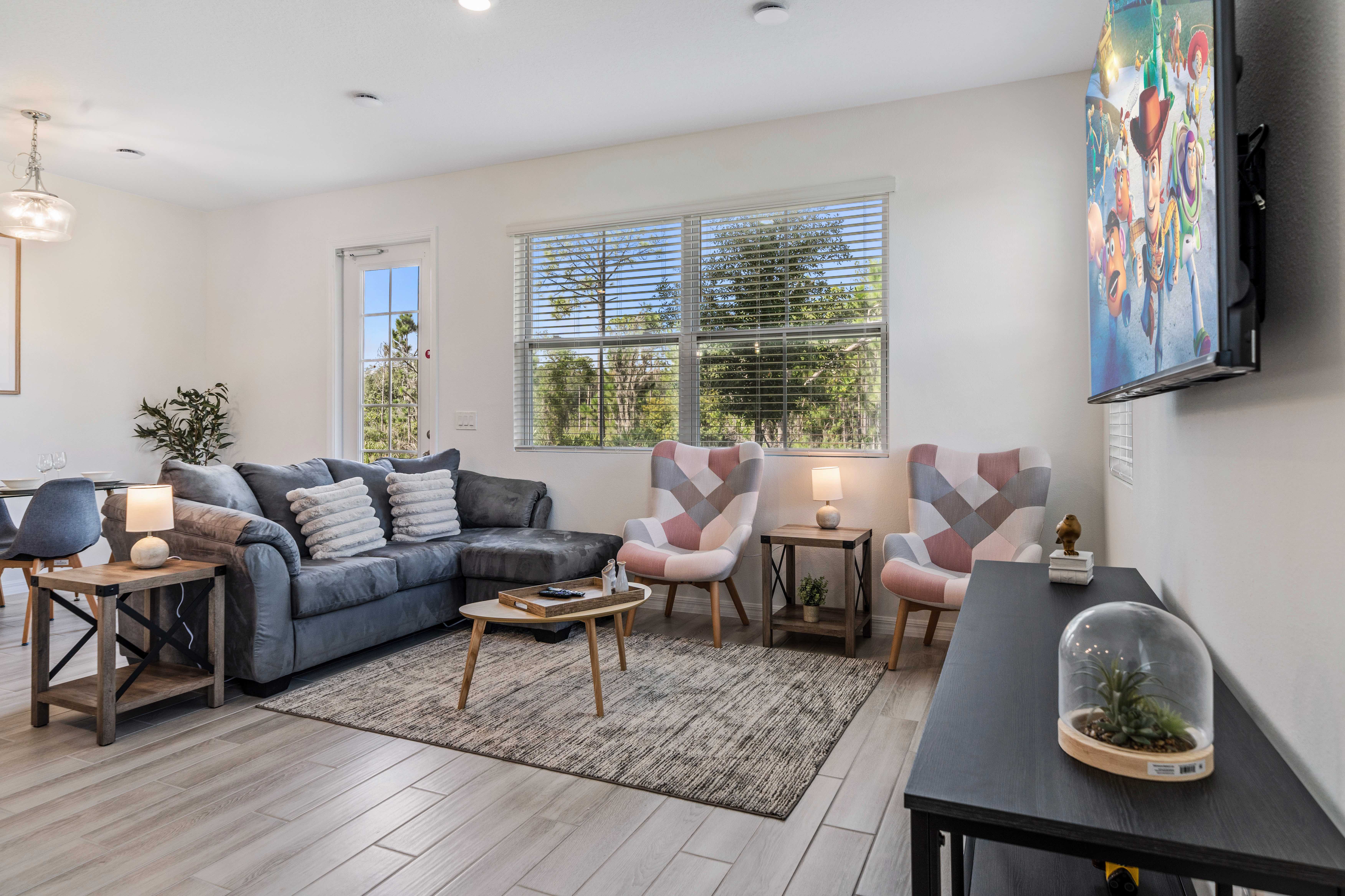 Relax in the spacious and bright living area with a cozy gray couch and large windows with views - Stylish armchairs and a coffee table for comfortable seating - Flat screen smart TV for entertainment with modern fixtures & plenty of natural light