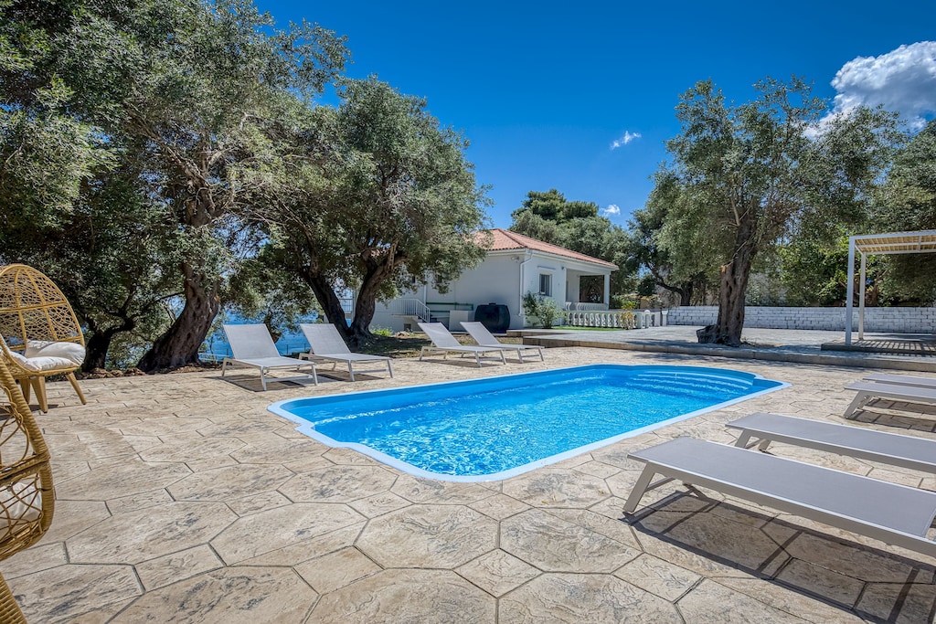 Pool, garden, and sea views with a glimpse of the villa’s beautiful exterior