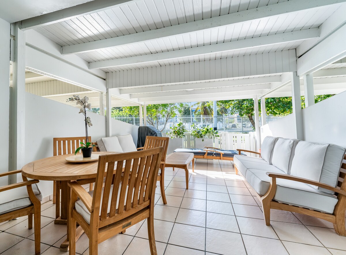 Garden view, Outdoor cushioned couch. Circular dining table with slat-back chairs