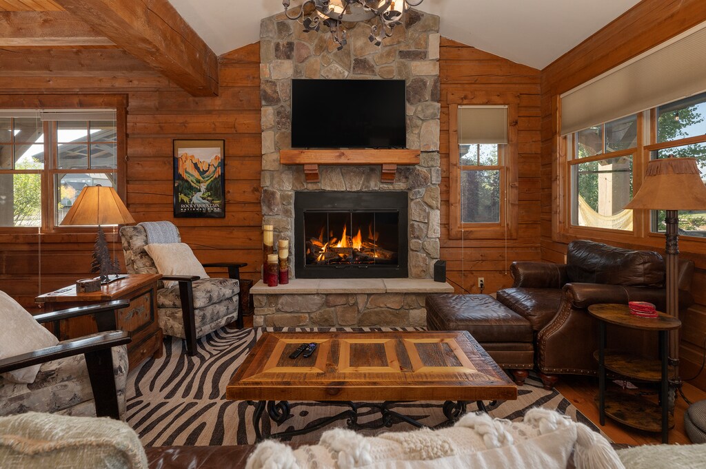 - Warm living room with stone fireplace and chandelier   - Leather chairs and rustic coffee table for gatherings   - Relax by the fire and enjoy cozy mountain evenings