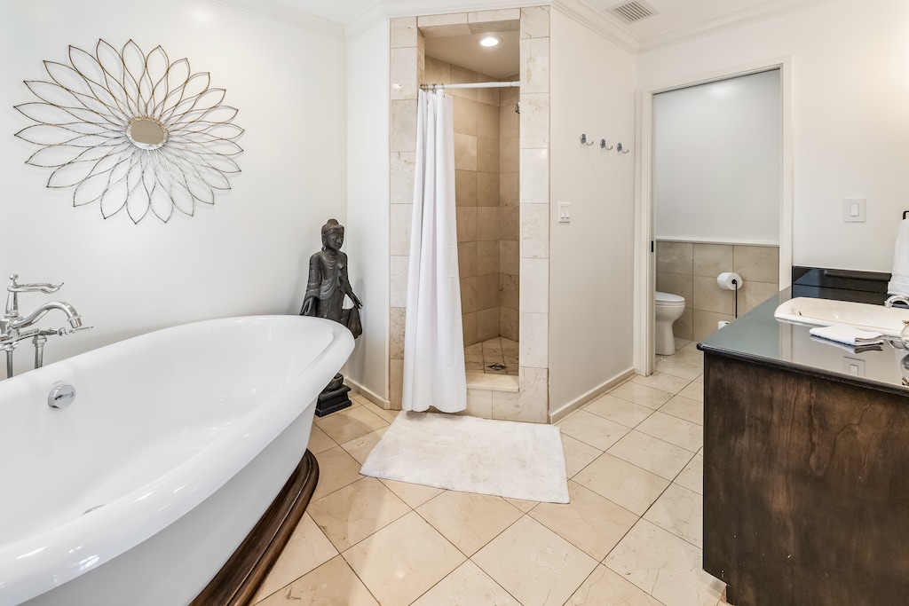 Elegant ensuite for Primary Bedroom 2 with a soaking tub, walk-in shower, and double vanity.