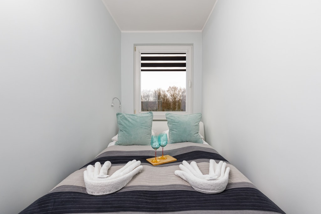 A stylish bedroom with a double bed, decorative pillows, and a bright minimalist design.
