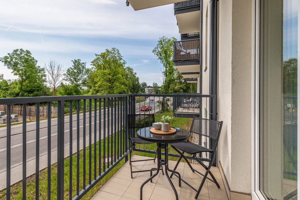 A balcony with a small table and chairs, overlooking greenery for a relaxing outdoor space.

