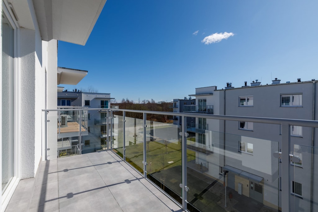 A spacious balcony overlooking modern apartment buildings. The outdoor space is perfect for fresh air and relaxation.