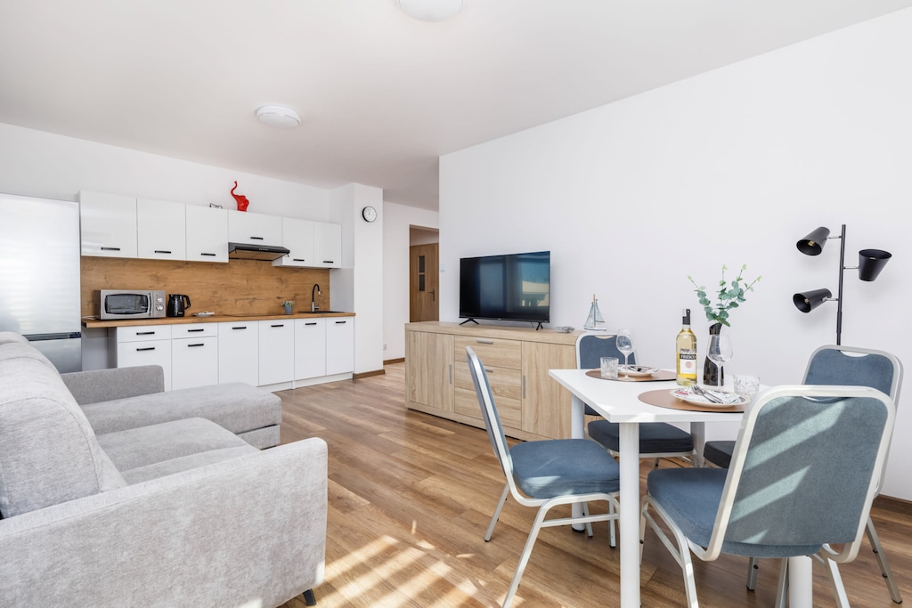 A modern living area with a sectional sofa and a round dining table. The room is decorated in neutral tones for a relaxing ambiance.