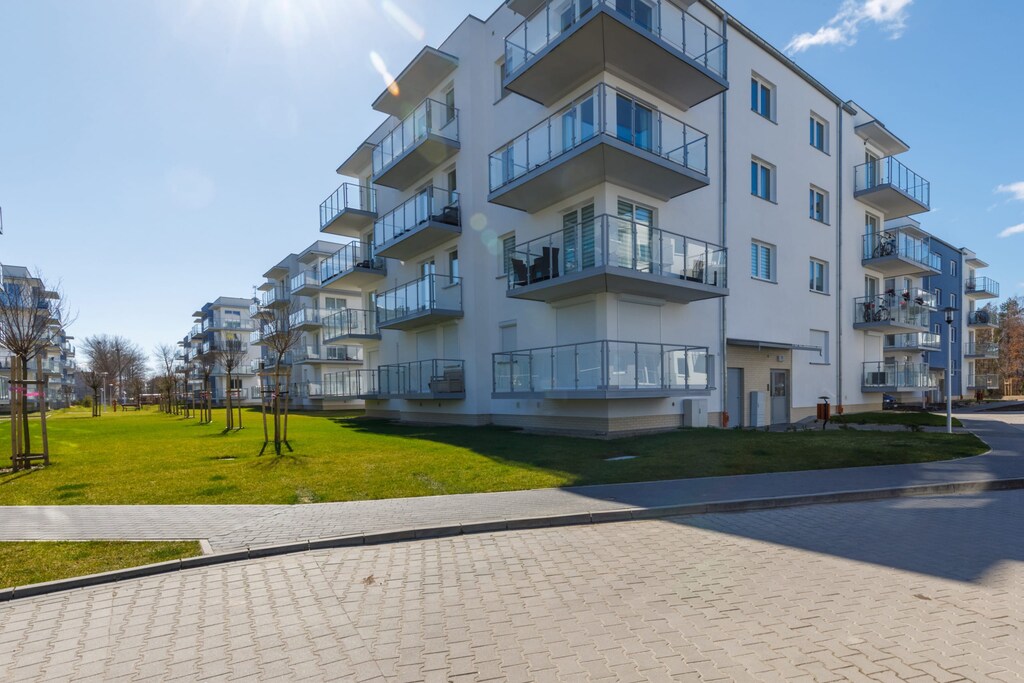  A modern apartment building with a clean and minimalist design. Green landscaping adds to the welcoming atmosphere.