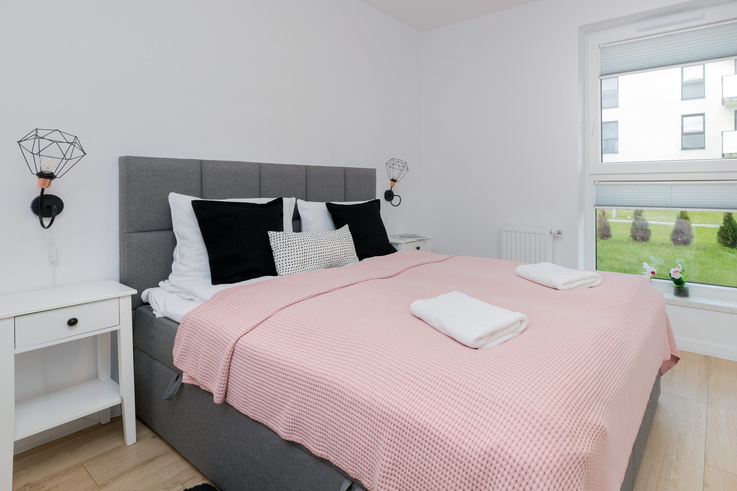 Cozy bedroom with pink bedding and thoughtful details, including nightstands and wall art. A peaceful space designed for ultimate comfort.