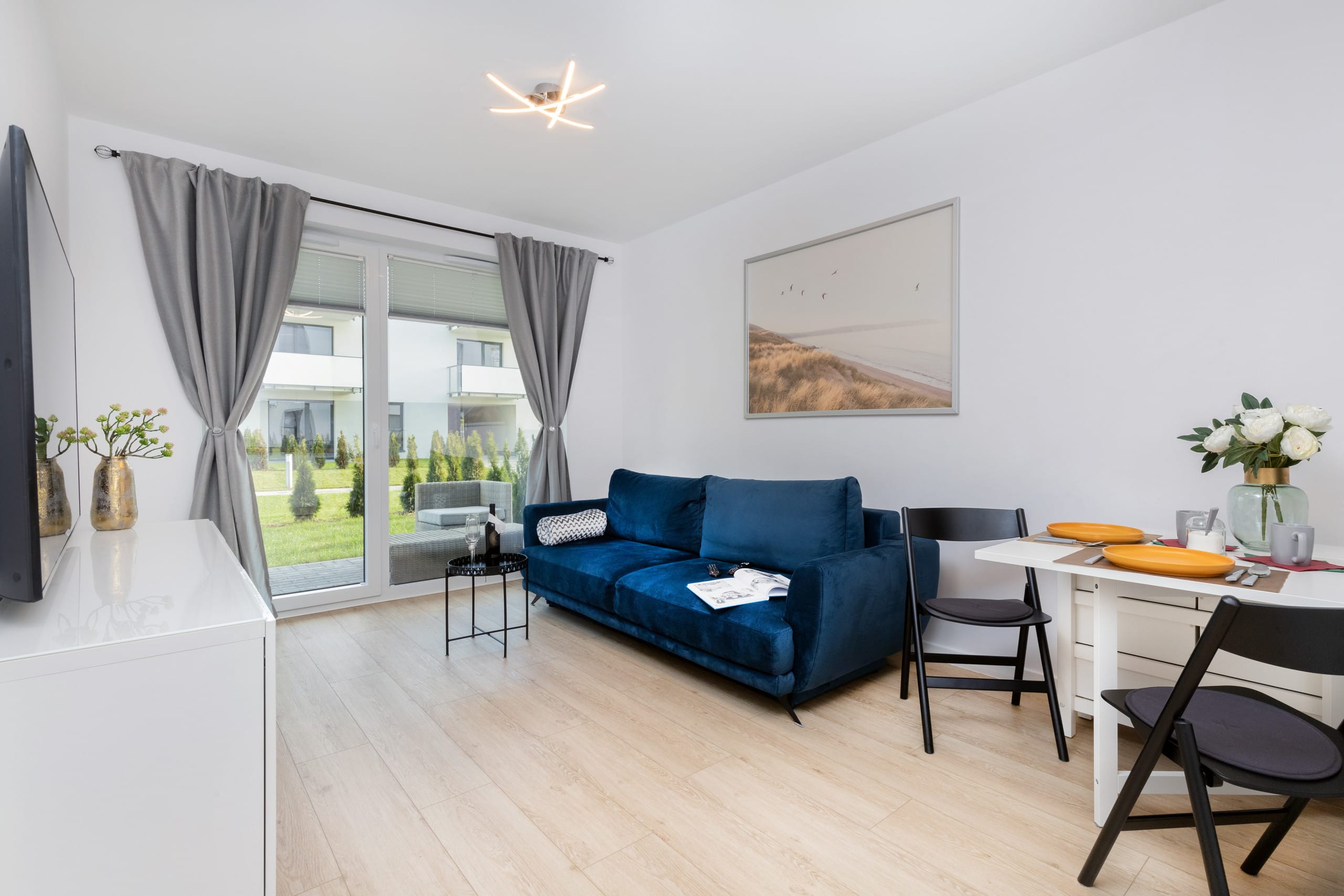 Elegant living area leading to a spacious balcony. The open layout, warm wooden accents, and soft furnishings make it ideal for unwinding or hosting guests.