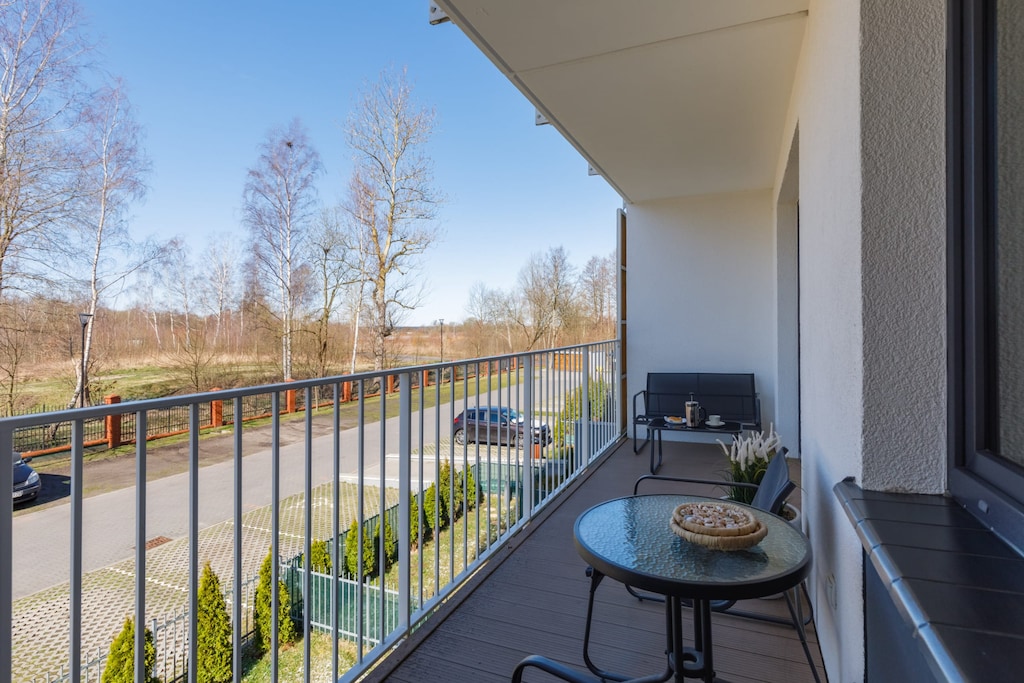 A balcony with a small table and chairs, offering a peaceful view of the surrounding greenery.
