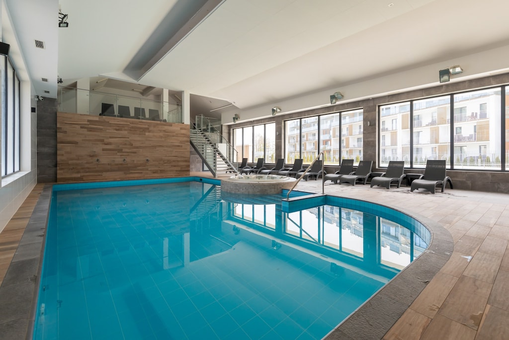 An indoor swimming pool with clear blue water, providing a serene environment for relaxation and exercise. The pool area has ample lighting and modern fixtures.