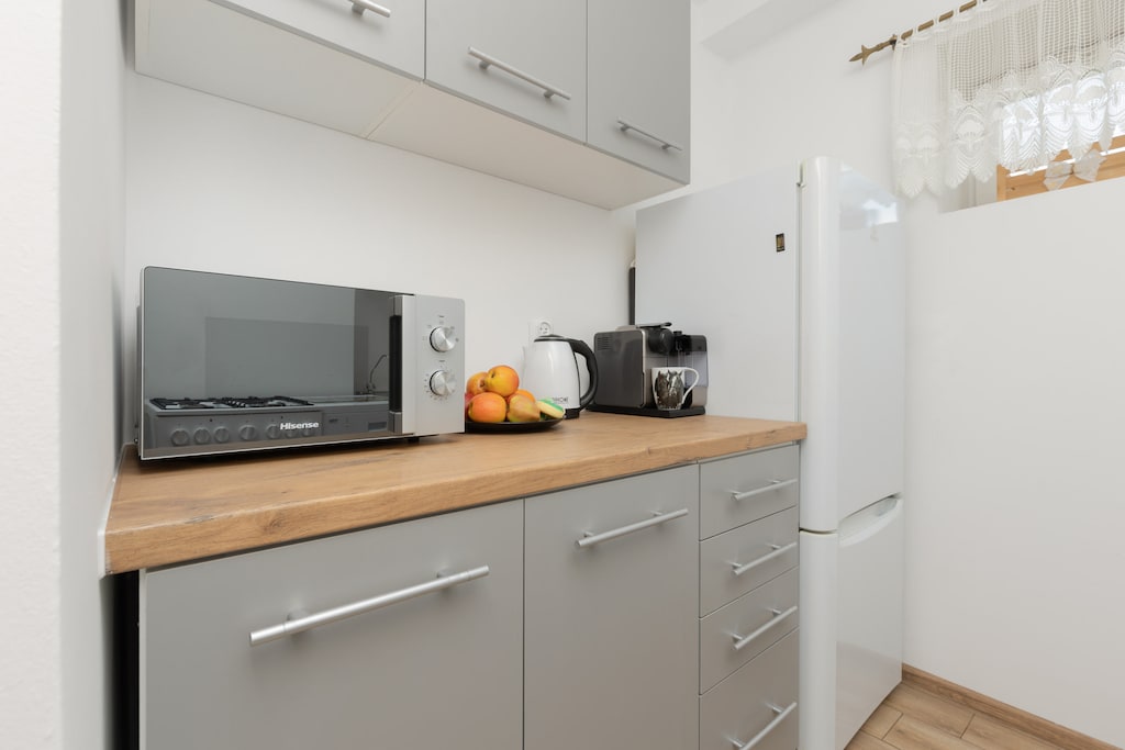 A compact kitchen area with a microwave, cabinets, and a clean, modern design, featuring light tones.