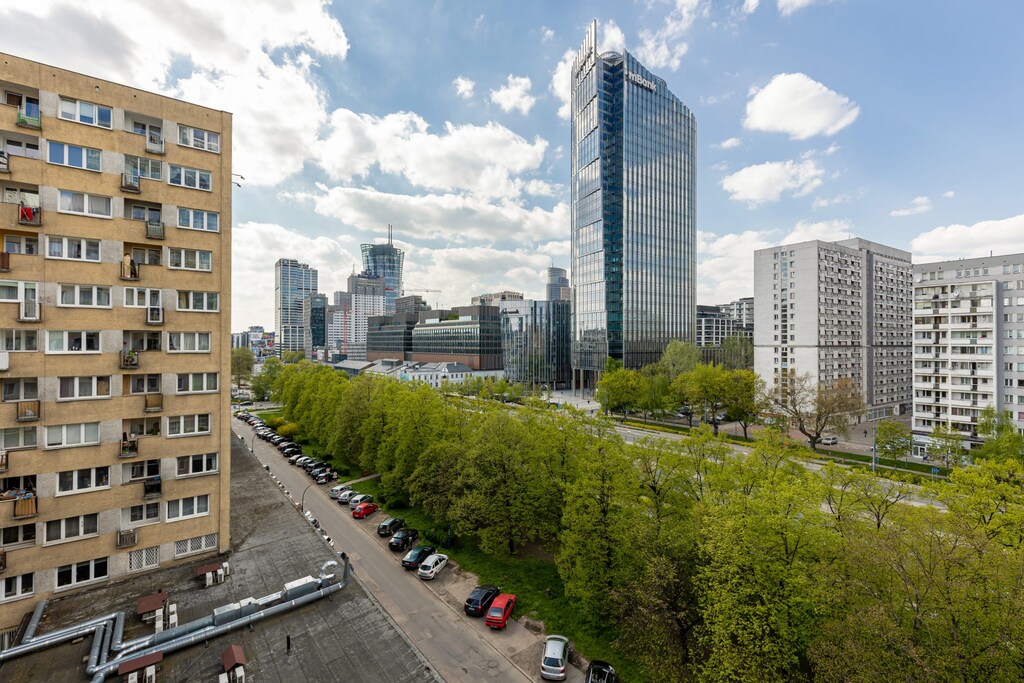 A view of a bustling urban street, with high-rise buildings and greenery visible.