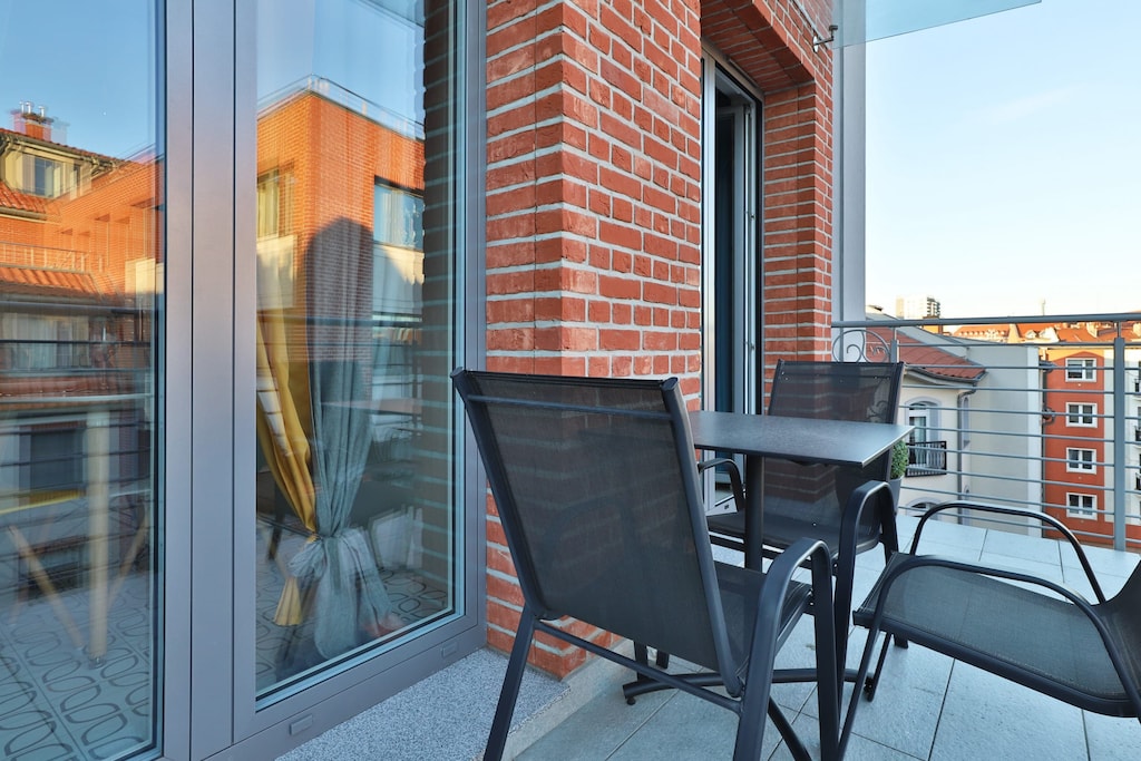 A spacious balcony with a table and chairs, offering city views. Perfect for enjoying outdoor meals or relaxing with a book.