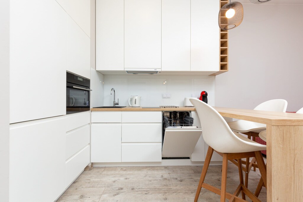 Elegant kitchen featuring white cabinetry, modern appliances, and an adjoining dining space for a functional lifestyle.