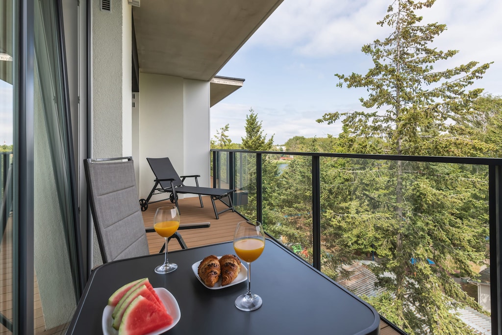 Private balcony with a small table and chairs, overlooking a green space.