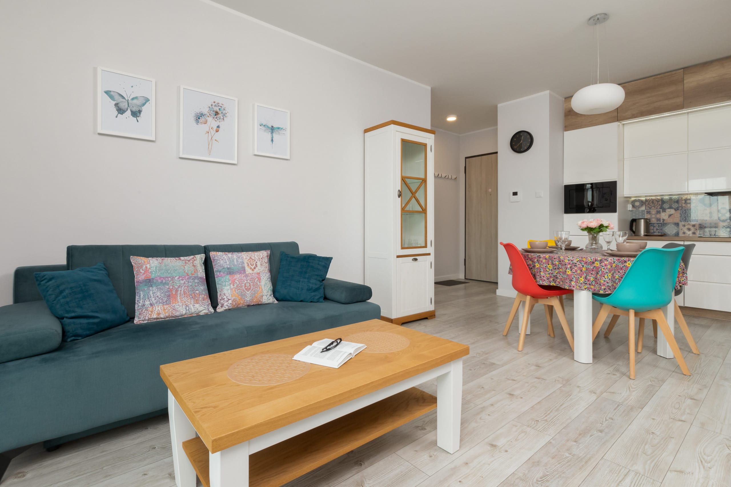 A modern living room with a teal sofa, a wooden coffee table, and wall decorations. The room has a bright and cozy atmosphere with stylish furniture. A modern living room with a teal sofa, a wooden coffee table, and wall decorations. The room has a bright and cozy atmosphere with stylish furniture.