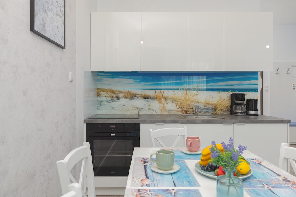 A sleek, modern kitchen with a dining table set for guests. The countertops are clean, with vibrant decor adding a pop of color.