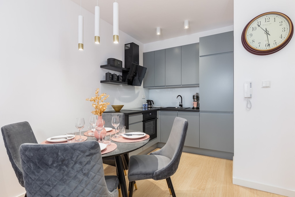 A dining area with a round table, stylish chairs, and a clock on the wall.
