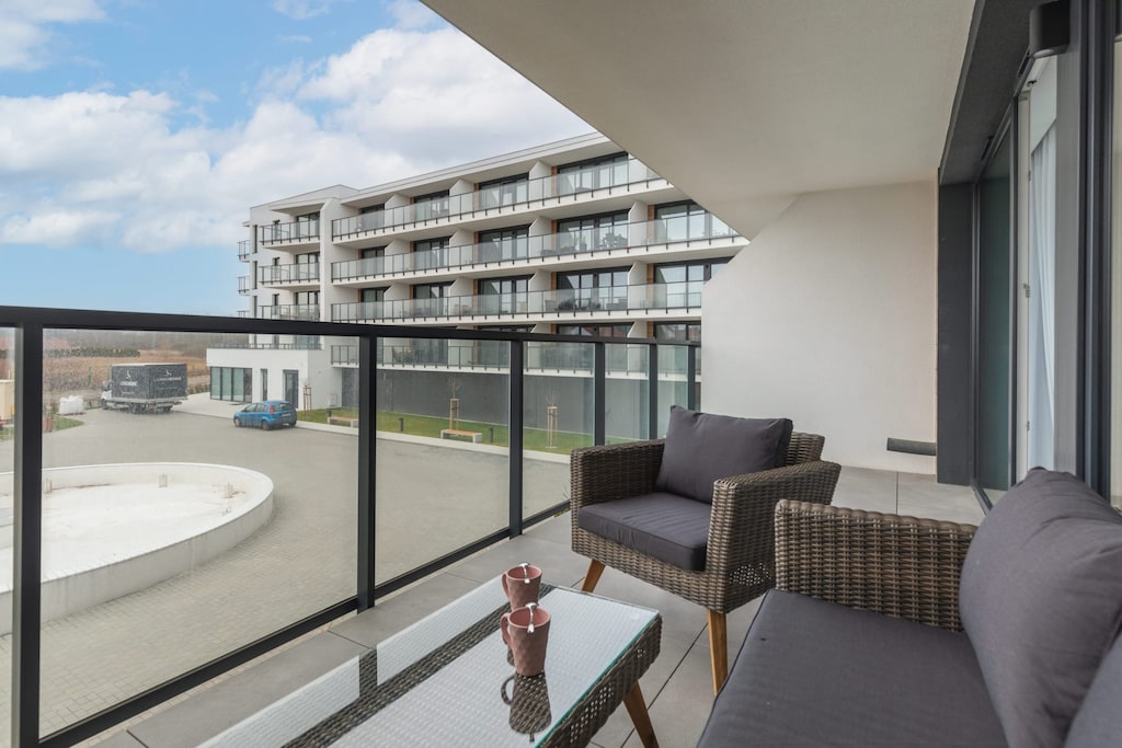 A spacious balcony with comfortable seating and a view of modern architecture.
