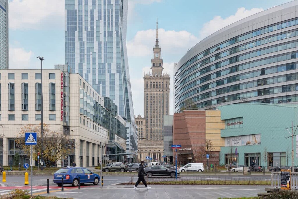 A bustling urban view of a busy street in the city center, showcasing the iconic Palace of Culture and Science alongside modern skyscrapers.