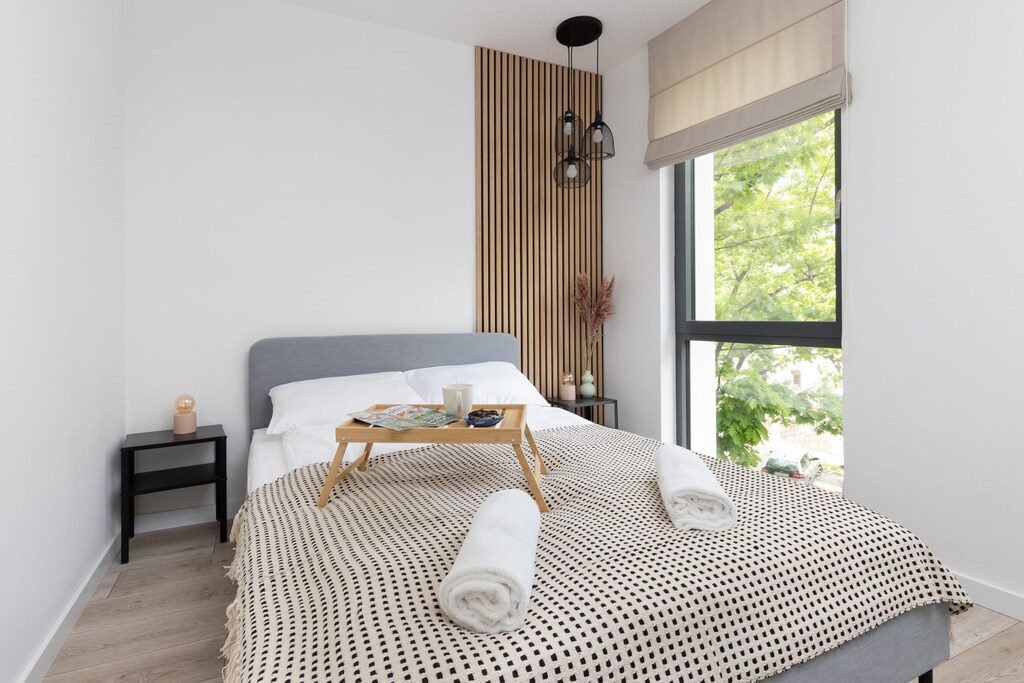 A stylish bedroom with a neatly made bed featuring a patterned blanket, soft pillows, and an inviting atmosphere created by natural lighting.