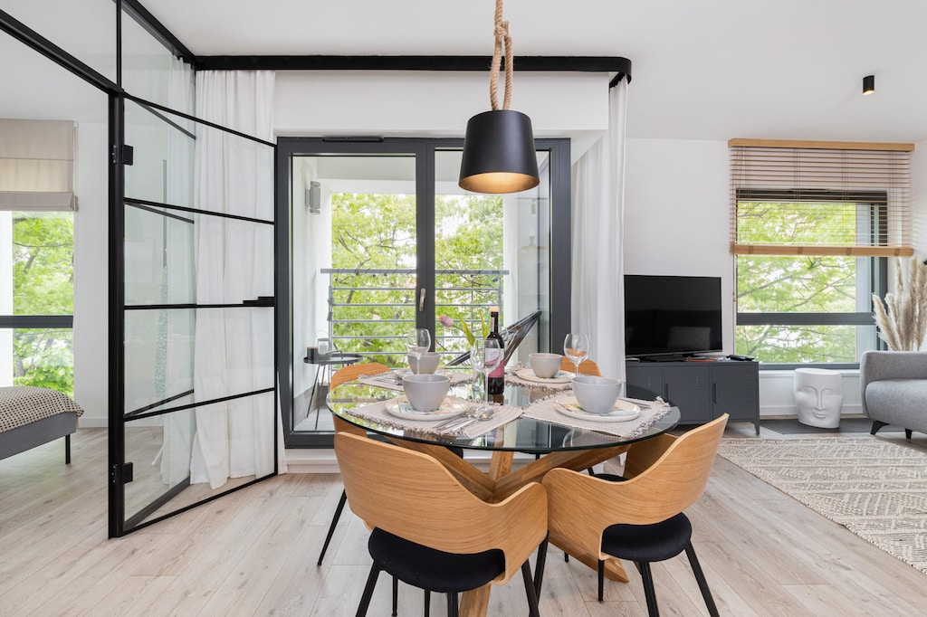 A beautifully set dining area with a round table, black chairs, and a large window, allowing ample sunlight to brighten the room.