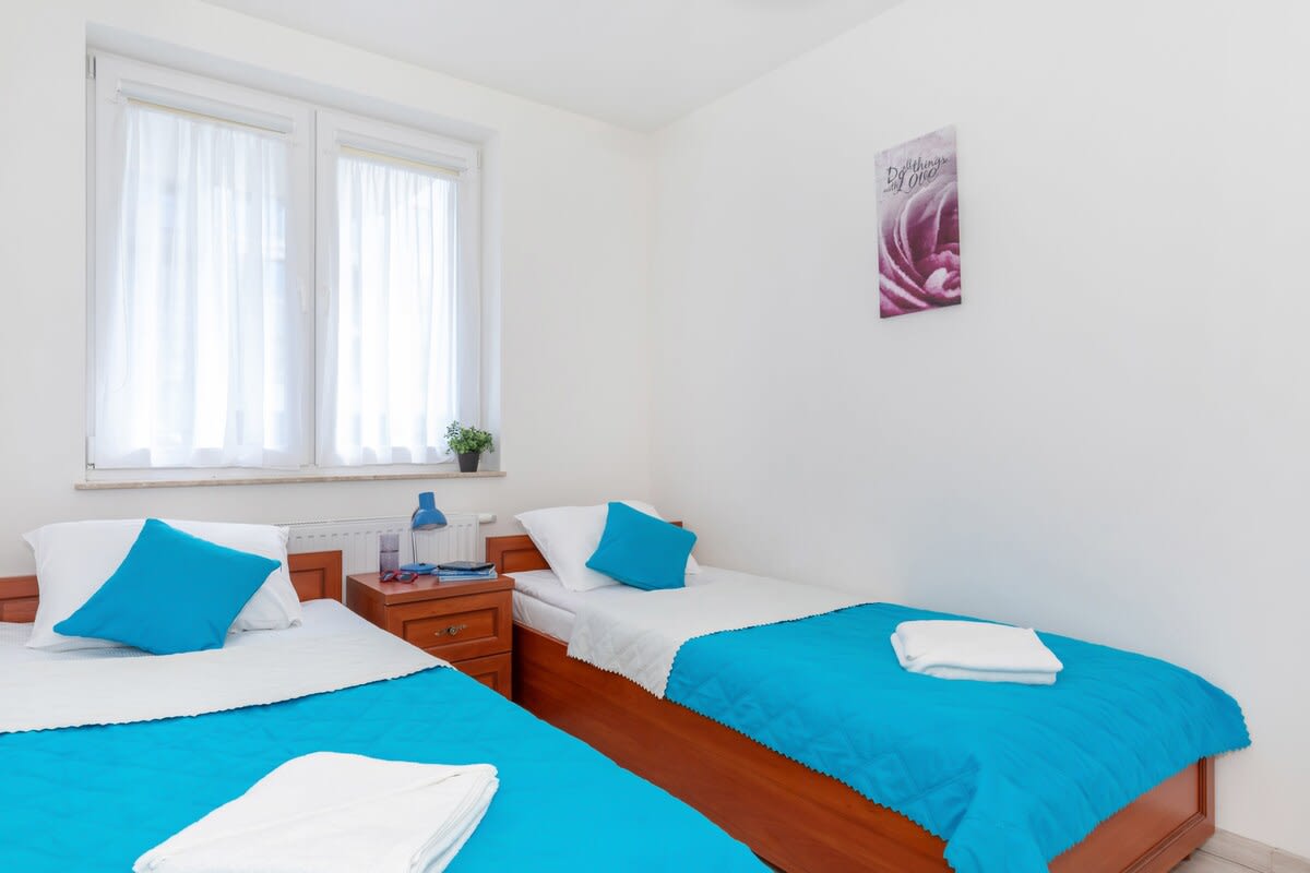 Bright and blue bedroom with two comfortable single beds and a bedside cabinet for handy trinkets.