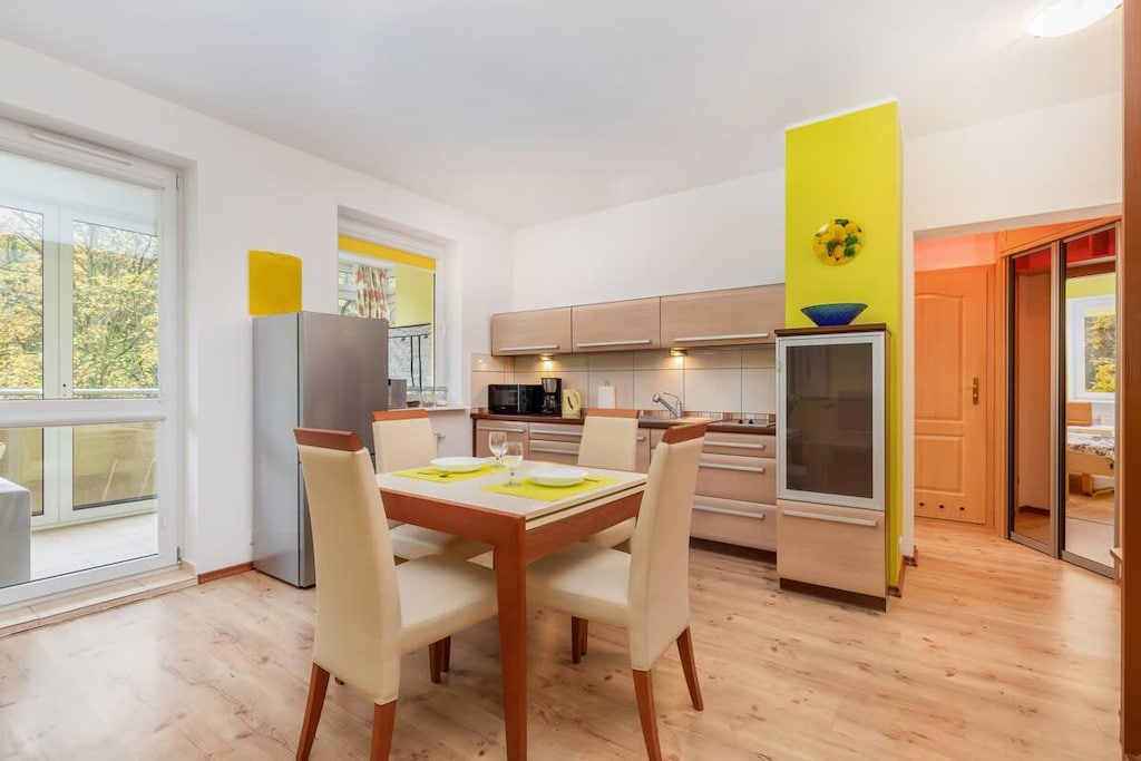 A combined dining area and kitchenette with a table for four, bright walls, and a view of the outdoors.