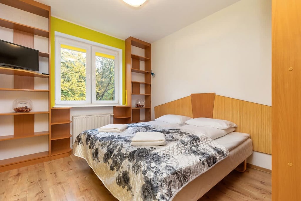 A bedroom featuring a large bed, wooden shelving, and built-in storage space along the wall.