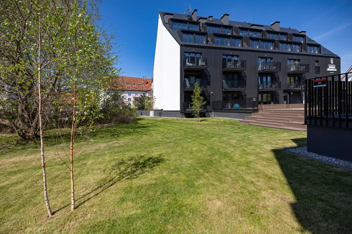 A spacious backyard with open green space, a patio, and a view of the surrounding buildings.