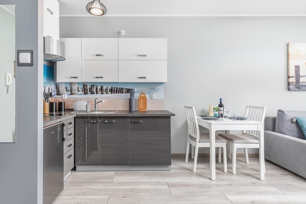 A sleek, modern kitchenette featuring gray cabinets, white countertops, and stainless-steel appliances.