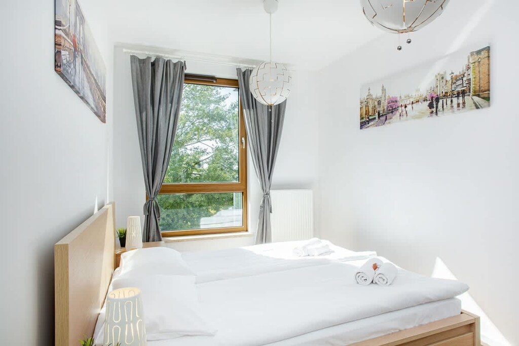 Cozy and well-lit bedroom with a large bed and window overlooking greenery.