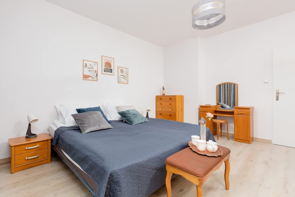 A spacious bedroom featuring a large bed with gray beddingand simple wall décor for a calm, inviting feel.