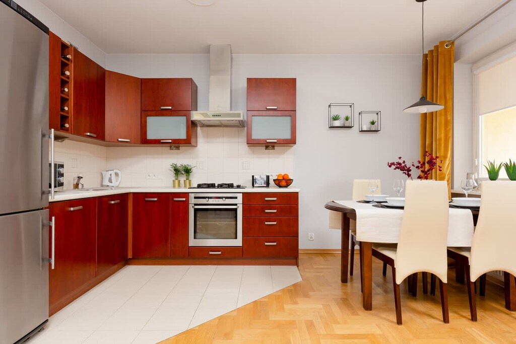 A compact kitchenette with red cabinets, bright countertops, and modern appliances, blending seamlessly into the living area.