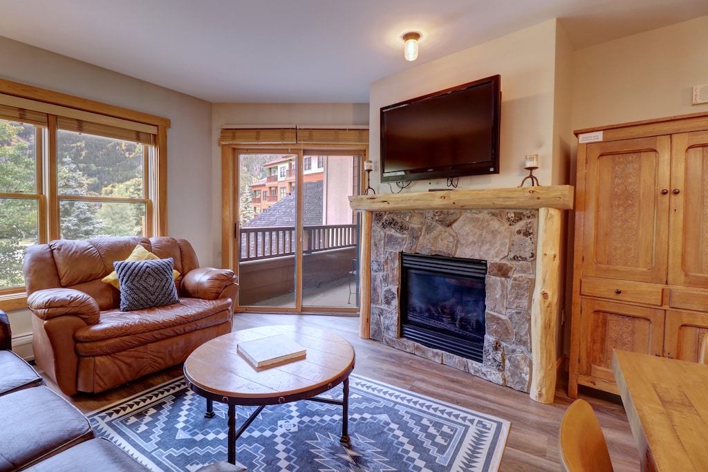Cozy living room with fireplace and TV, access to private balcony.