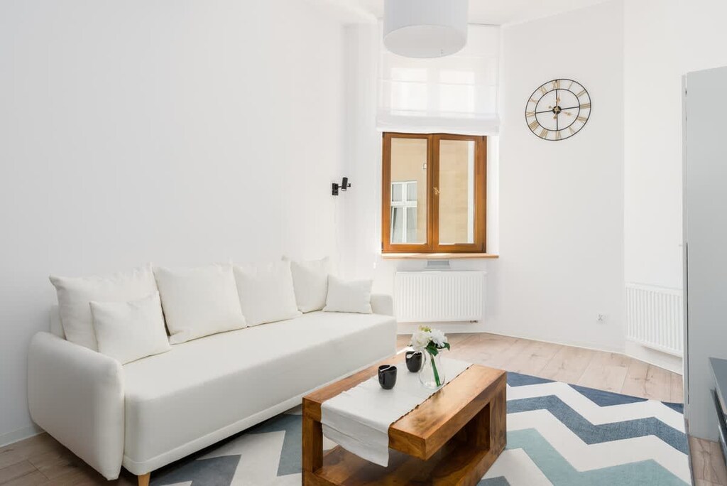 Another perspective of the living room, showcasing a sleek design with a white sofa, decorative rug, and TV unit.