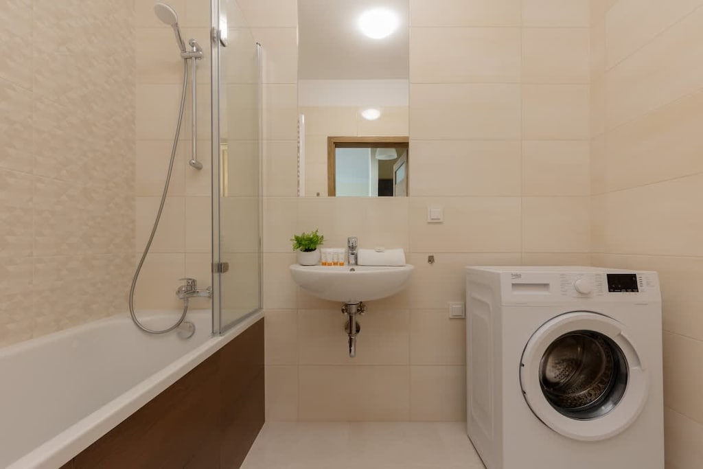 A modern bathroom equipped with a bathtub, a washing machine, and a sleek design.
