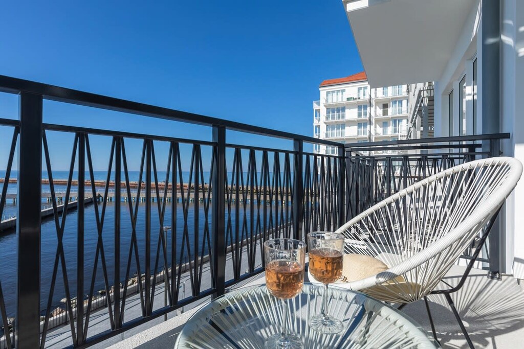 A balcony with a comfortable seating area, offering picturesque views of the waterfront and surrounding buildings.

