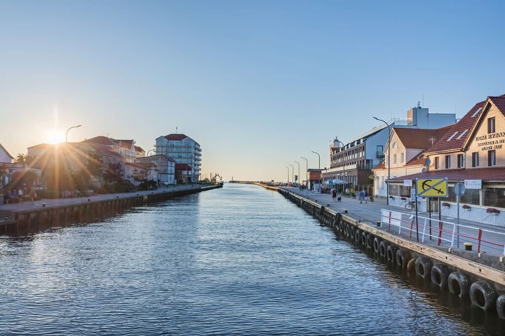 A peaceful canal view during sunset, showcasing charming waterfront architecture and reflections on the water.

