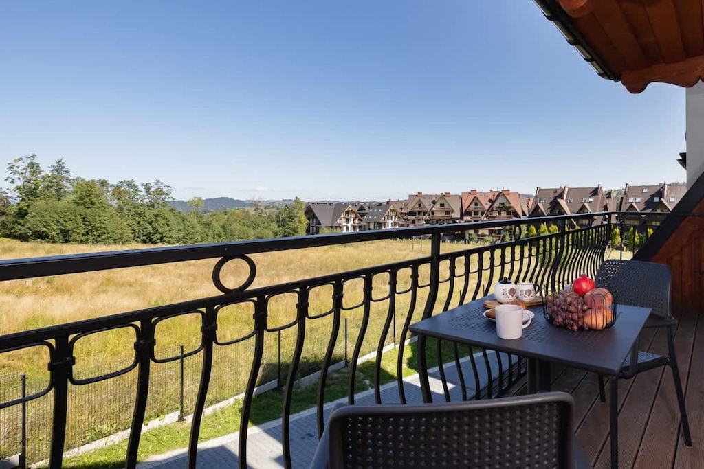 A balcony view overlooking a picturesque landscape, with a table set for two, ideal for enjoying the scenery.
