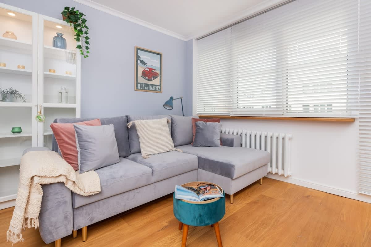 Bright living room with a cozy sofa, decorative pillows, and a coffee table, featuring soft, pastel decor.