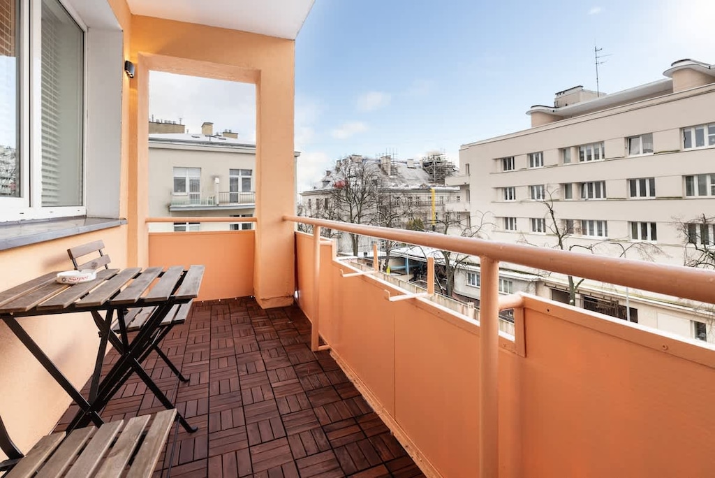 Balcony with outdoor seating and a table, offering a view over the nearby city buildings.