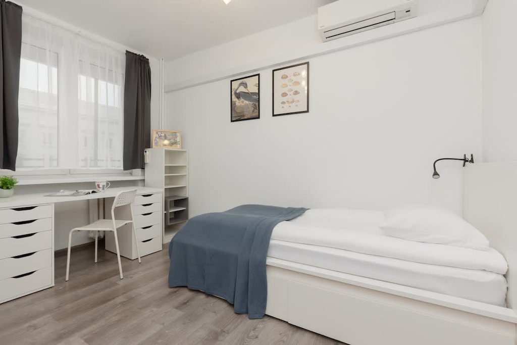 A stylish bedroom with a white bed, blue bedding, a desk, and framed artwork on the walls.