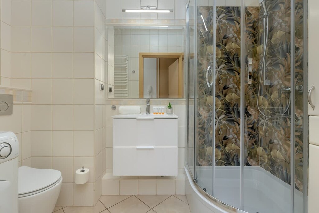 A bathroom with a glass shower enclosure, toilet, and decorative tiles.