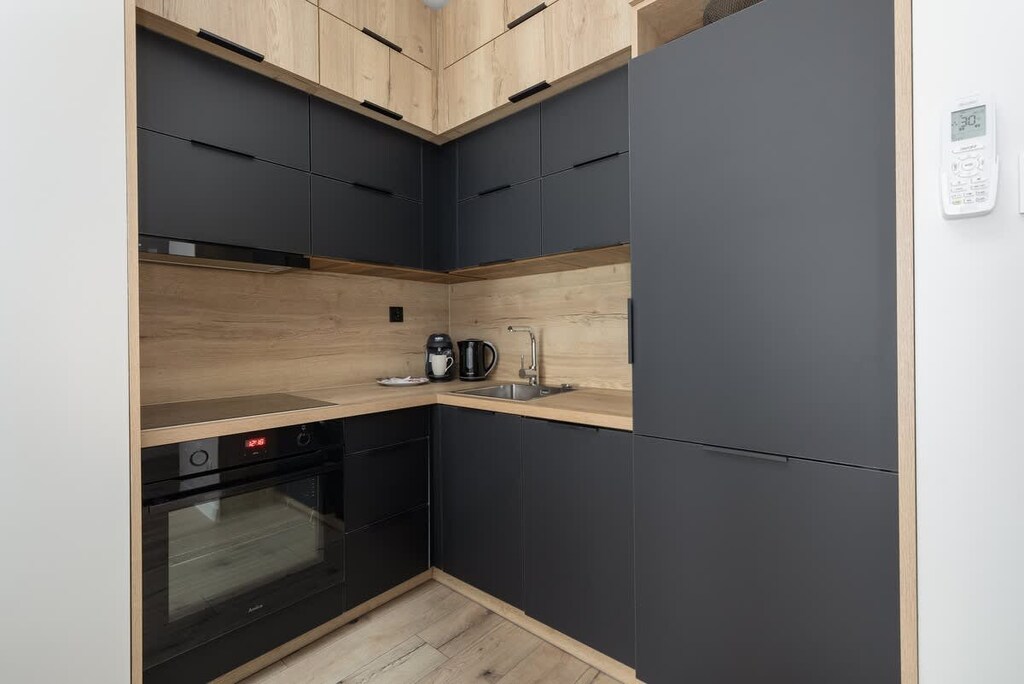 A sleek kitchen with black cabinets, wooden countertops, and built-in appliances, blending functionality with contemporary design.

