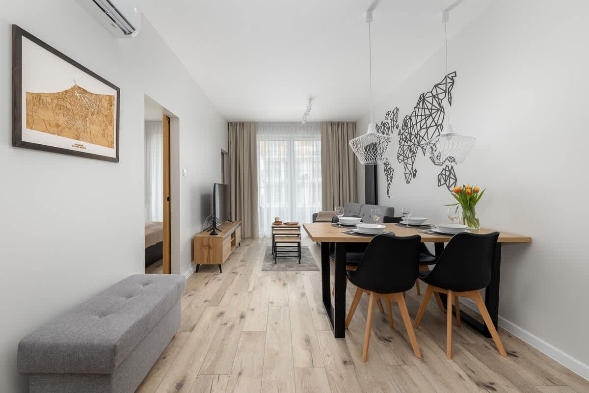 A bright and spacious dining area with a stylish wooden table, comfortable seating, and framed artwork on the wall.

