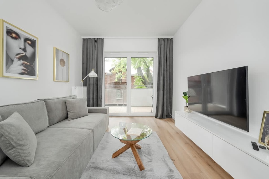 A cozy living room space with a sofa, coffee table, and large window. Ideal for relaxing or watching TV.