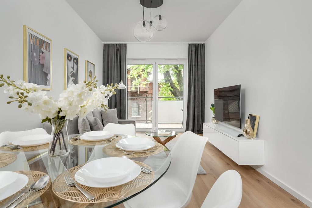 An elegant living room with a sofa, TV, and dining area. Full of natural light and stylish décor.