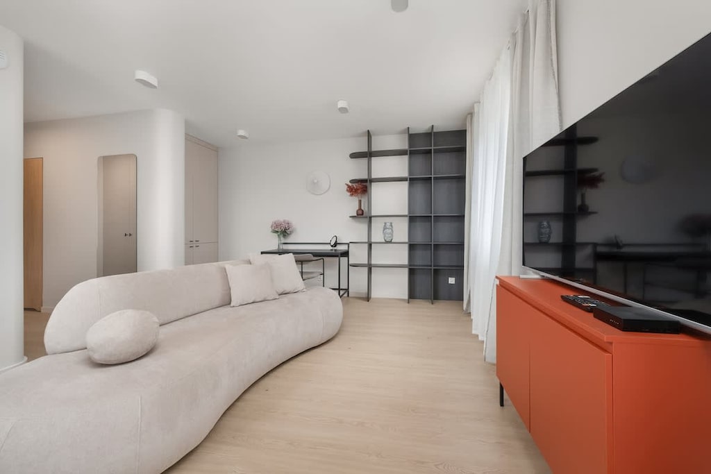 Living room with bed and TV
Bright space with a cozy bed, flat-screen TV, and access to the balcony.