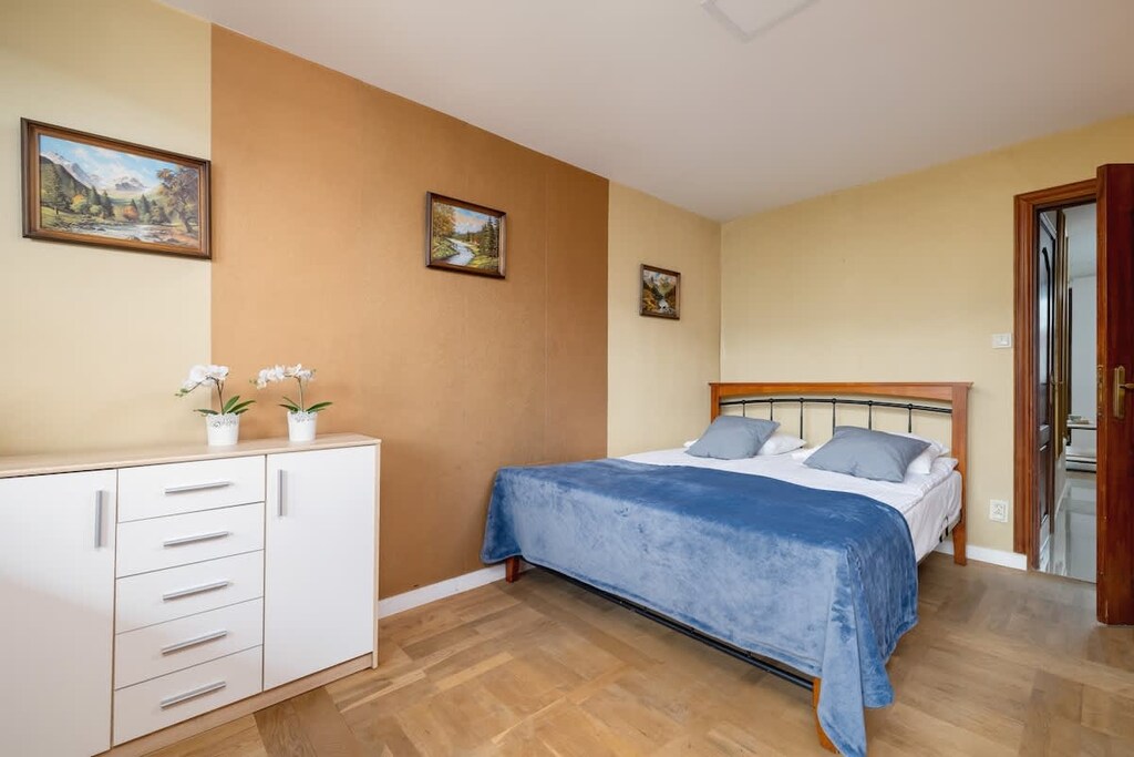 A softly illuminated bedroom with a double bed, light peach-colored walls, and practical furnishings that emphasize comfort.